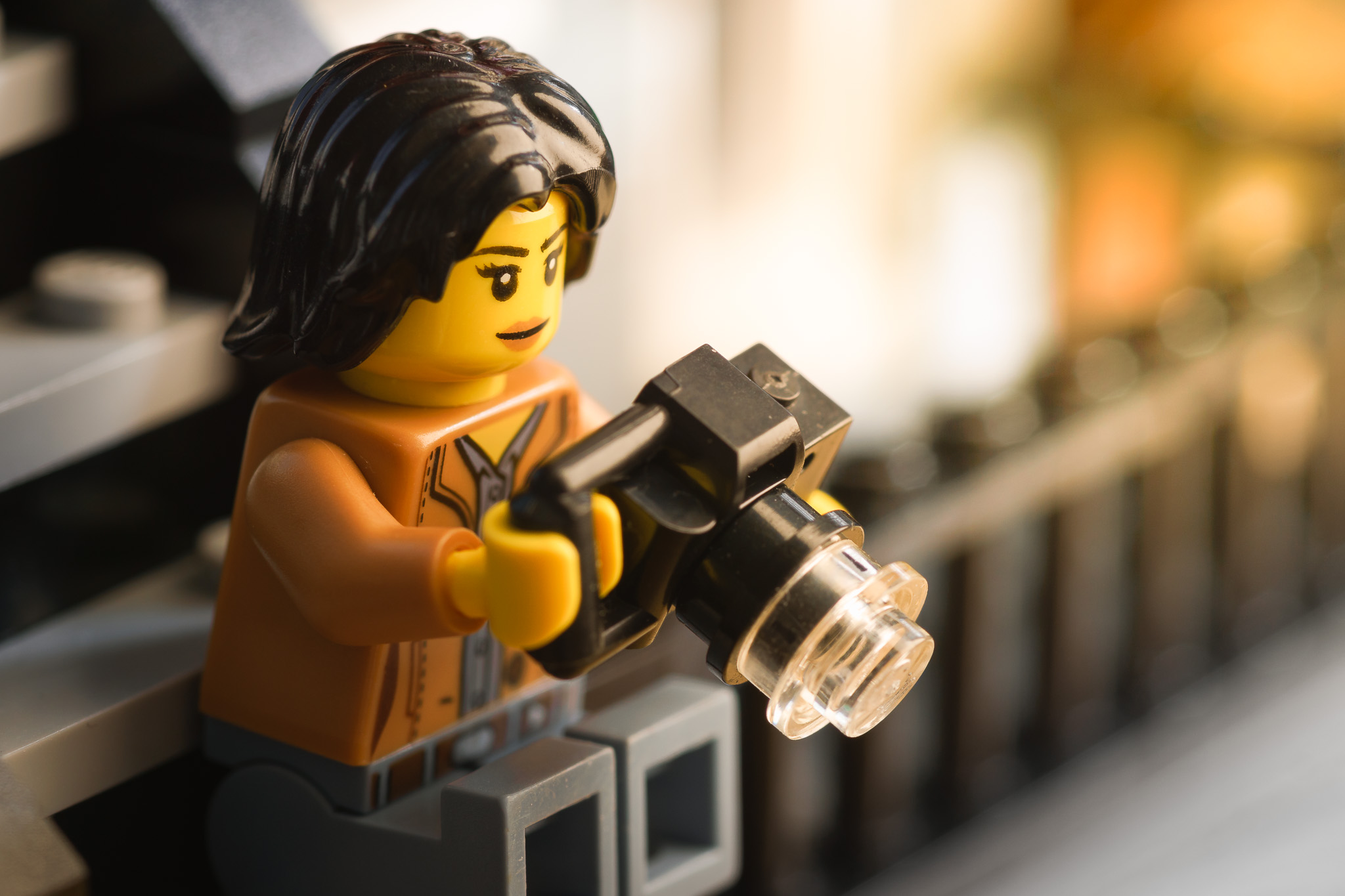 Photo of LEGO female minifigure holding a camera while sitting on a stoop