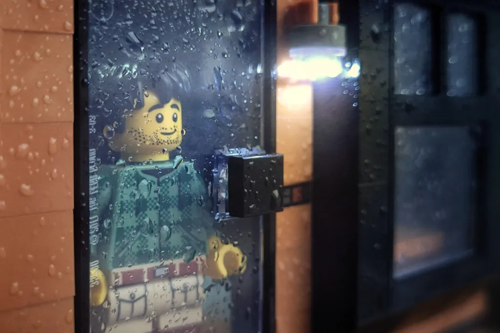 LEGO minifigure looking out of a door at the rain