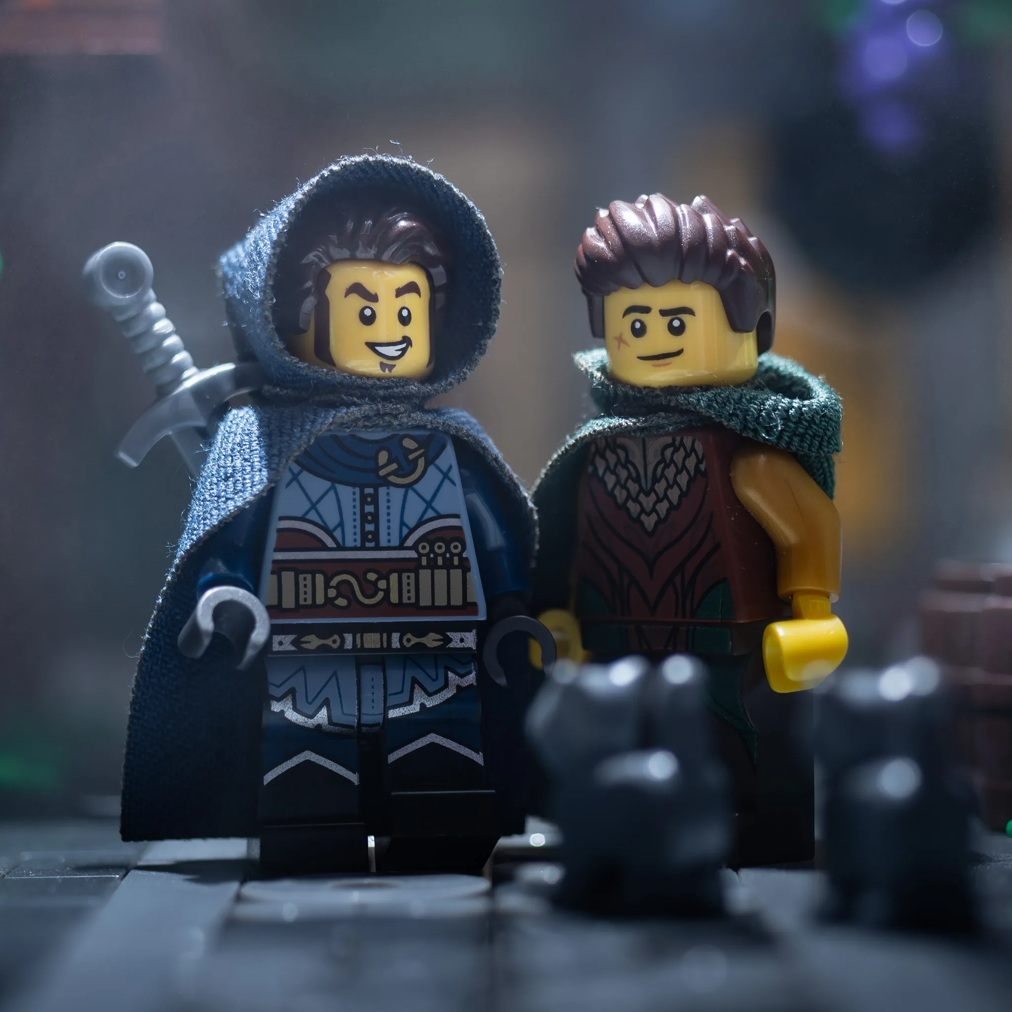 LEGO medieval minifigures wearing hooded cloaks and sheathed sword