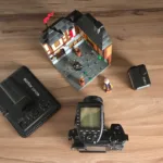 Camera, LEGO model, LEGO minifigs, and lights in a flat lay overhead shot