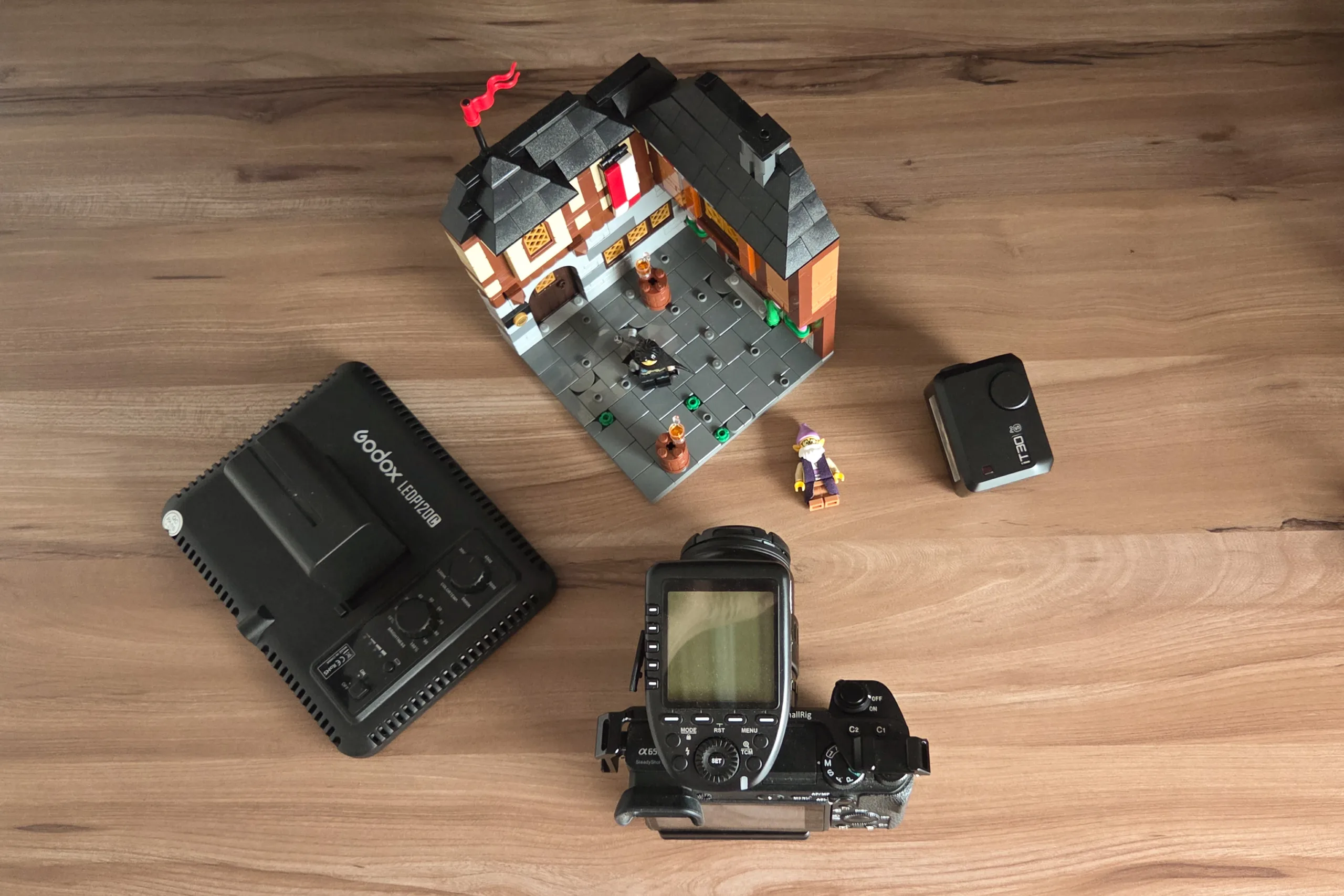 Camera, LEGO model, LEGO minifigs, and lights in a flat lay overhead shot